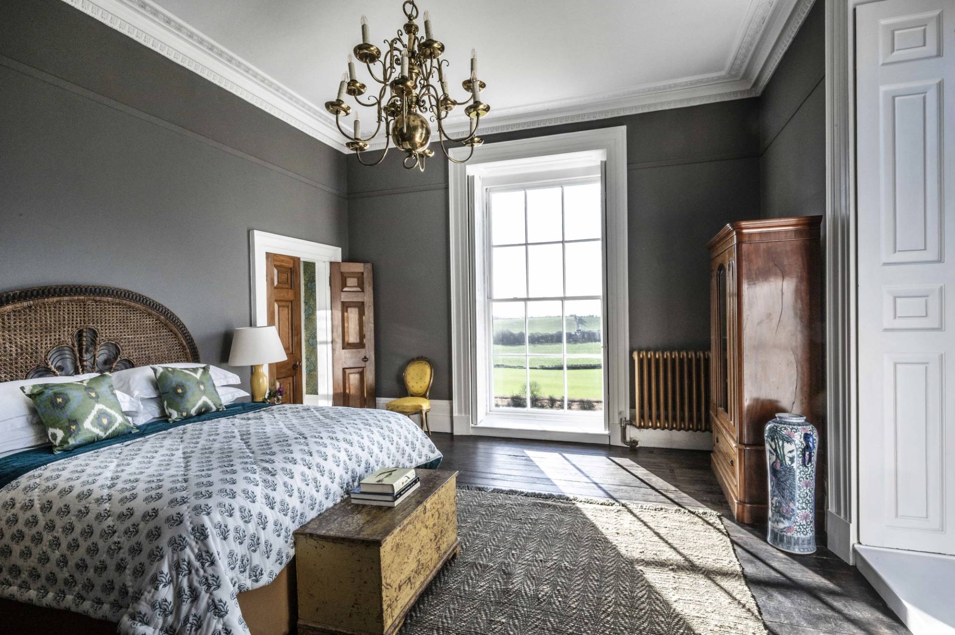 Moody charcoal grey bedroom location featuring a wooden bed frame, brass chandelier, and sash window views, ideal for cinematic film sets via Love Locations LE7.