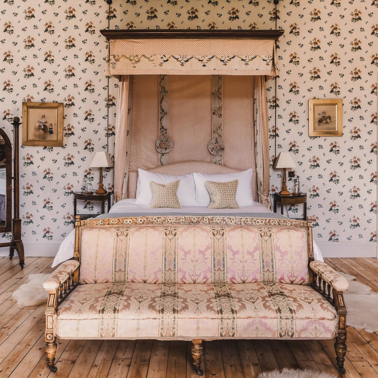 Grand historic castle master bedroom suite featuring an ornate upholstered canopy four-poster bed, floral toile wallpaper, matching patterned sofa bench, and timber floorboards in Fife, Love Locations KY15.