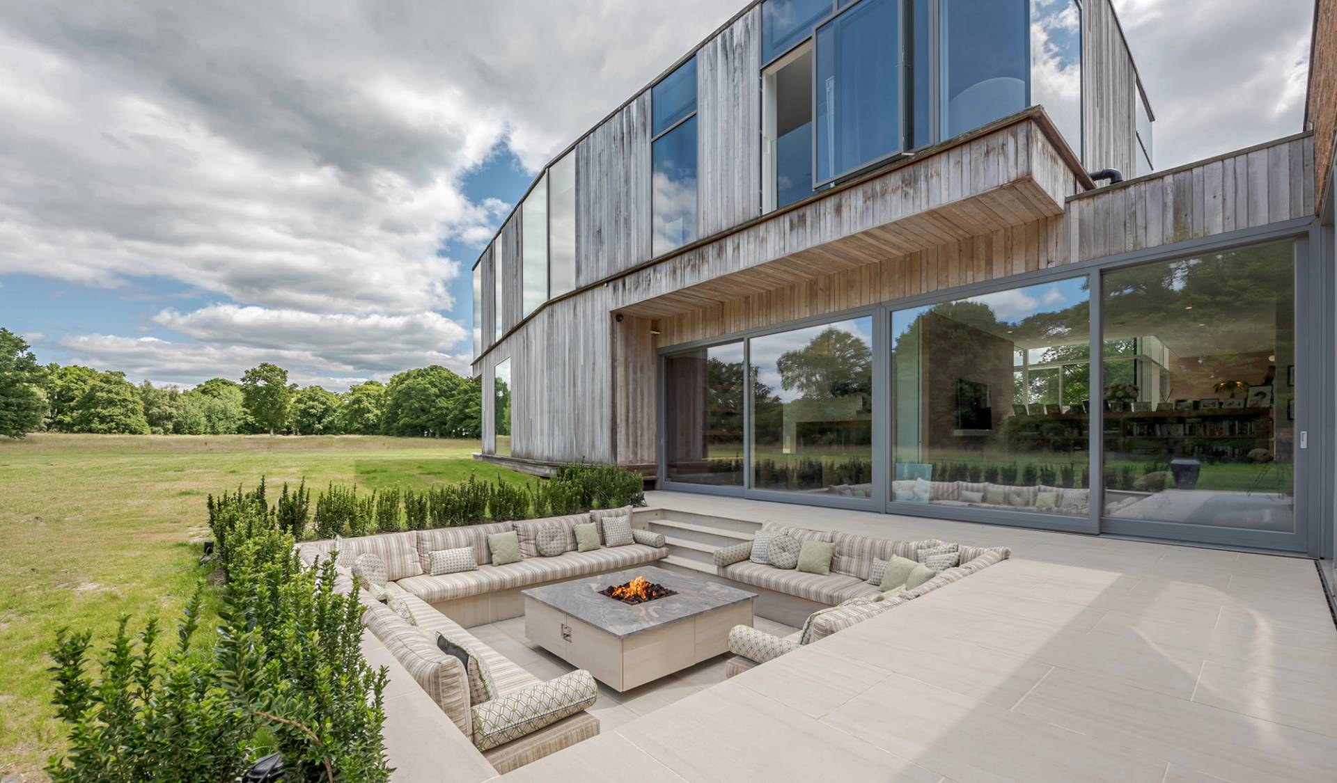 Love Locations modern courtyard location Godalming Surrey GU8: High-concept architectural sunken stone seating area with a central square fire pit, a highly cinematic setting for TV and film.