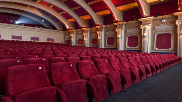 Side profile view of the tiered red theater seating and decorative classic wall pillars inside The Ritzy Screen 1 cinema venue from Love Locations.