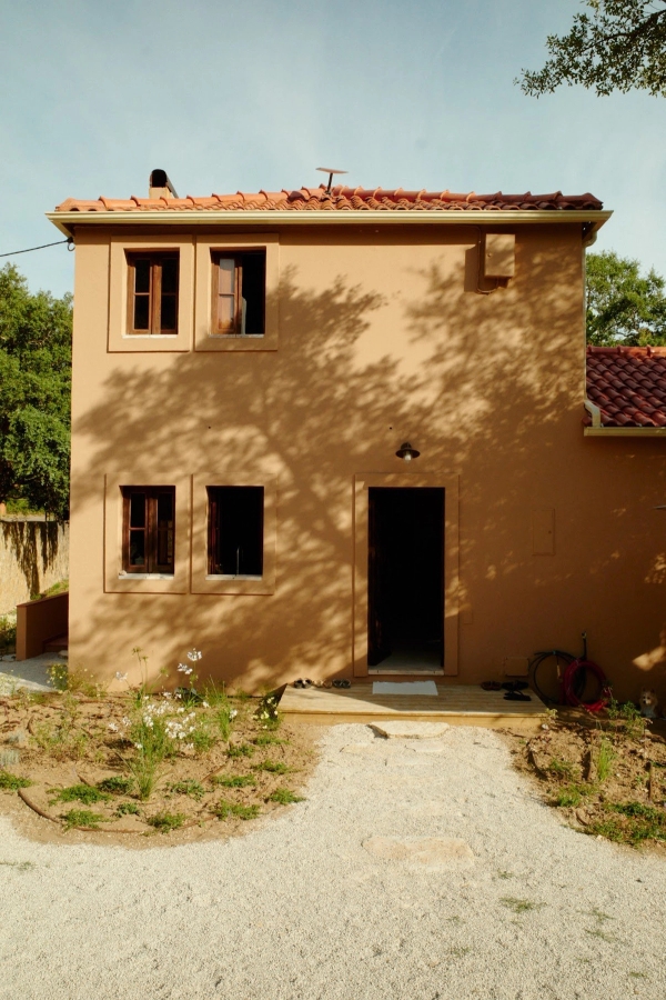 Warm terracotta plaster villa facade featuring wooden shuttered windows and gravel pathway, Love Locations 2705-064.