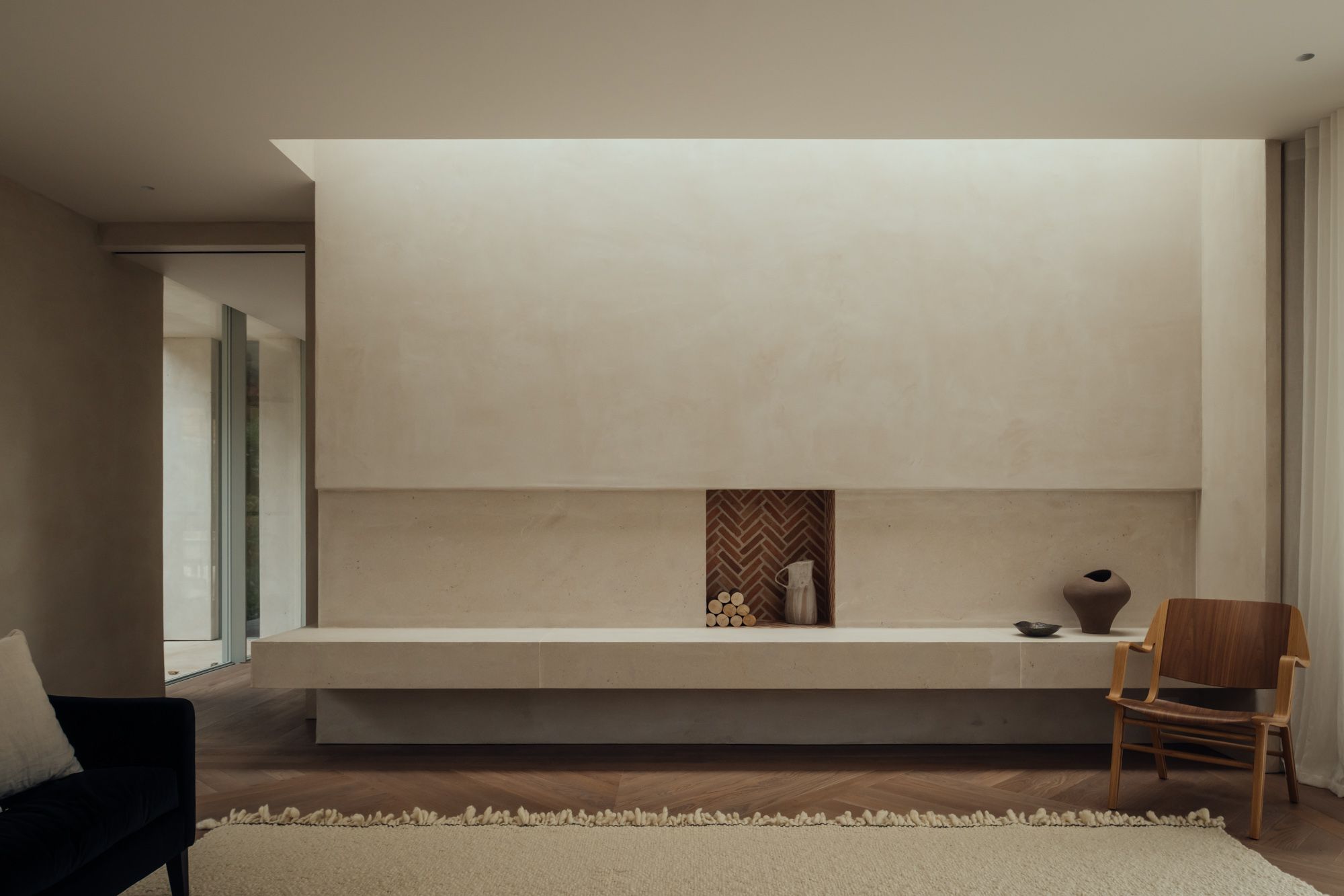 Chalk House – contemporary stone fireplace area with inset shelf, modern vases, a neutral rug, and a modern chair, showcasing a modern rustic look