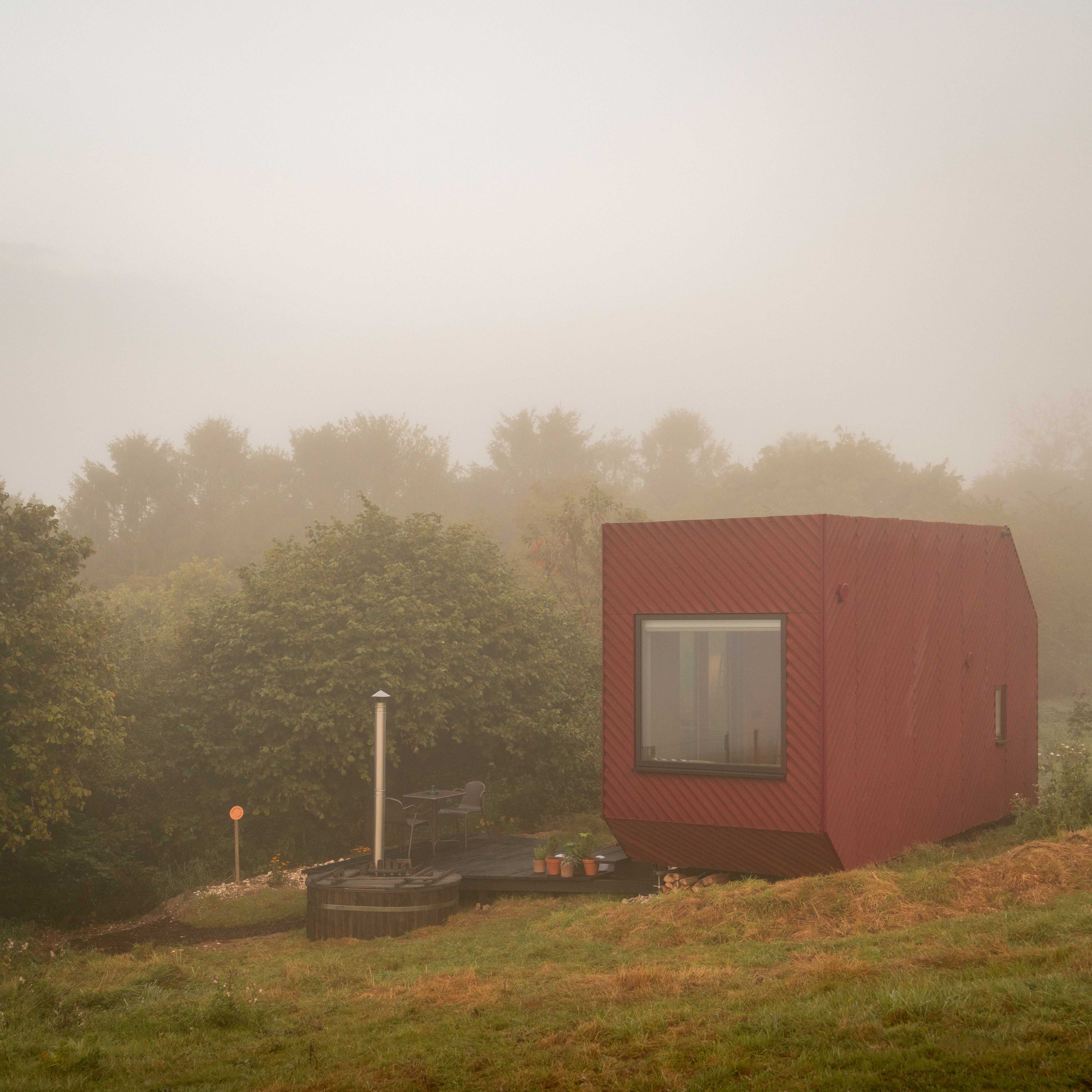 Modern rust-clad cabin in a Dorset field, known as Bide Cabin, surrounded by open countryside – ideal for off-grid retreats and shoots.