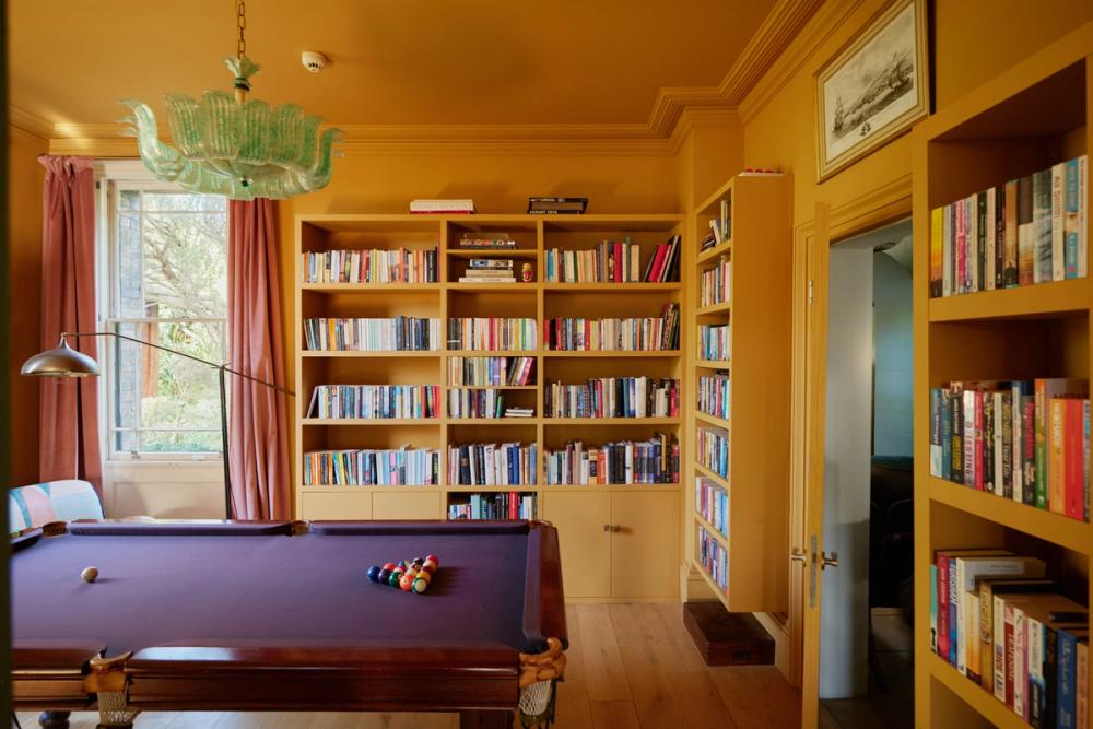 Yellow room with built in bookcases and pool table