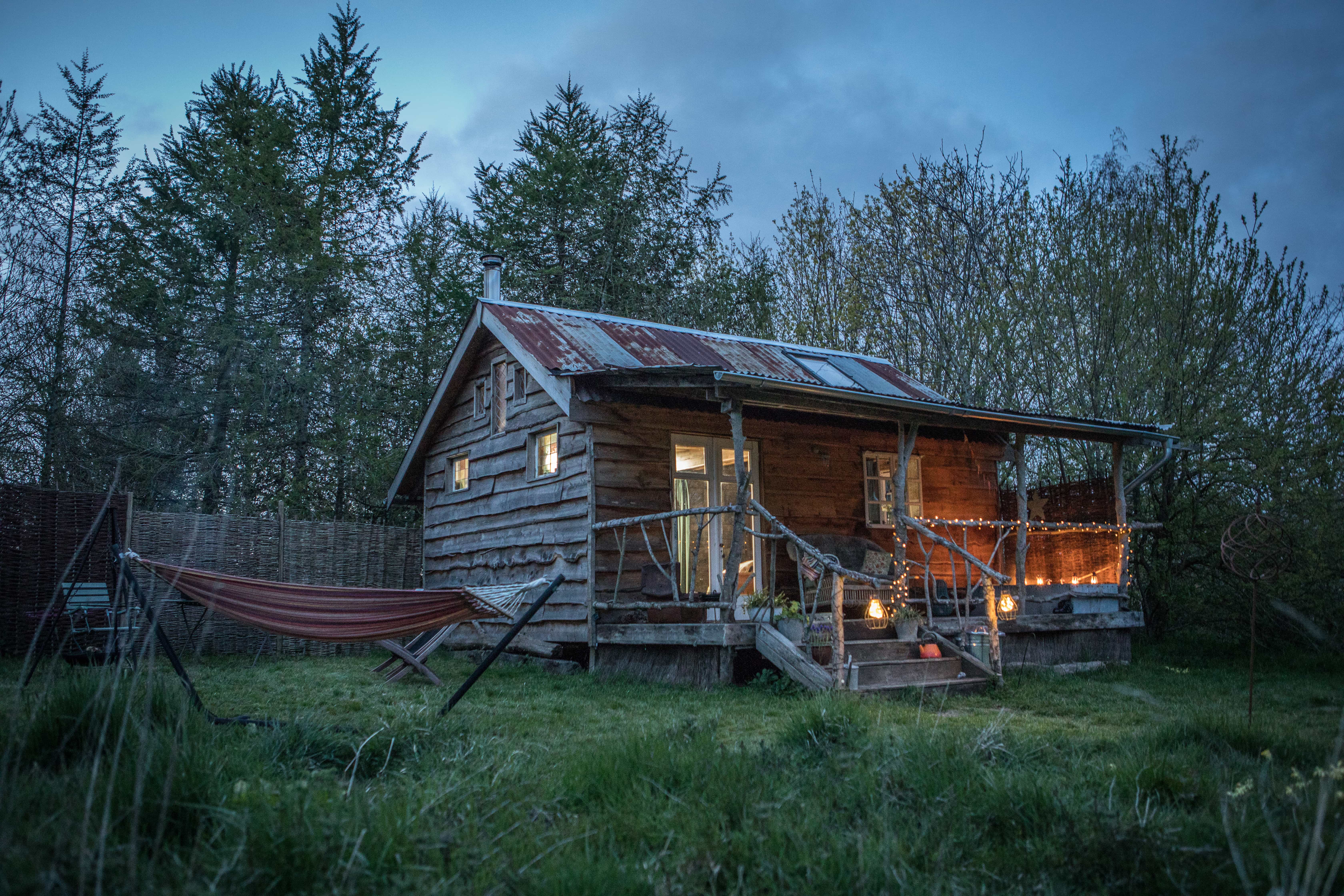 Albion Cabin glowing under the stars. Reclaimed materials, lakeside views, and twinkling lights make this Norfolk hideaway feel truly magical after dark.