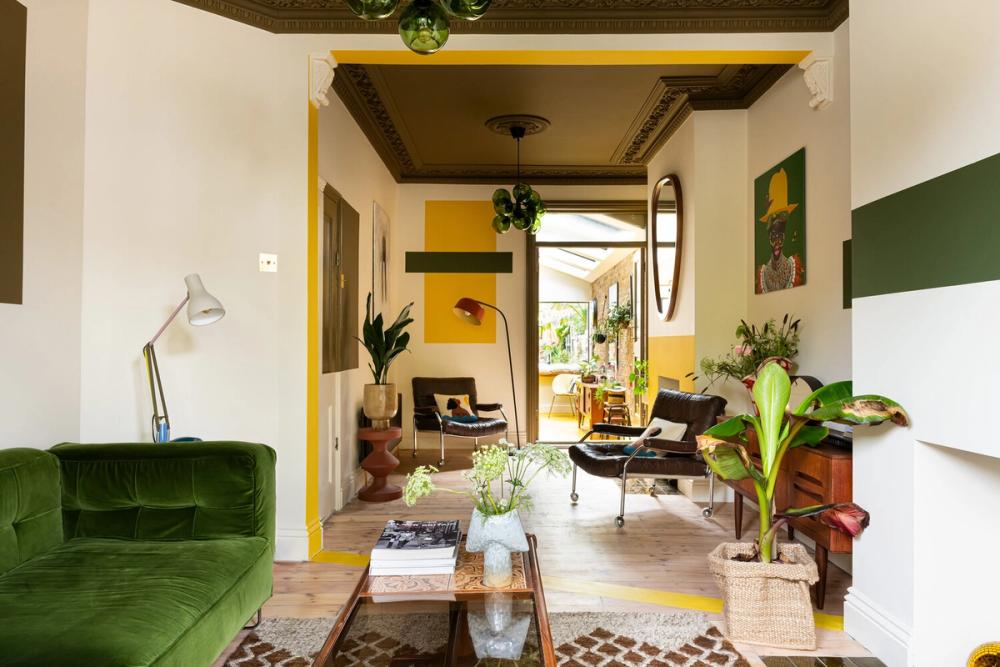 Afriqican inspired bright living space, yellow & green geo shapes painted on wall.