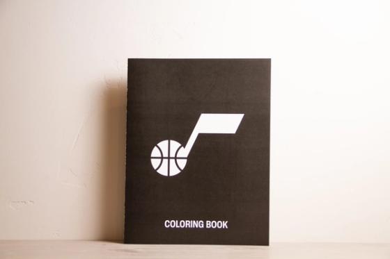 Utah Jazz coloring book standing upright, black cover with the white note-and-basketball logo and the words "Coloring Book."