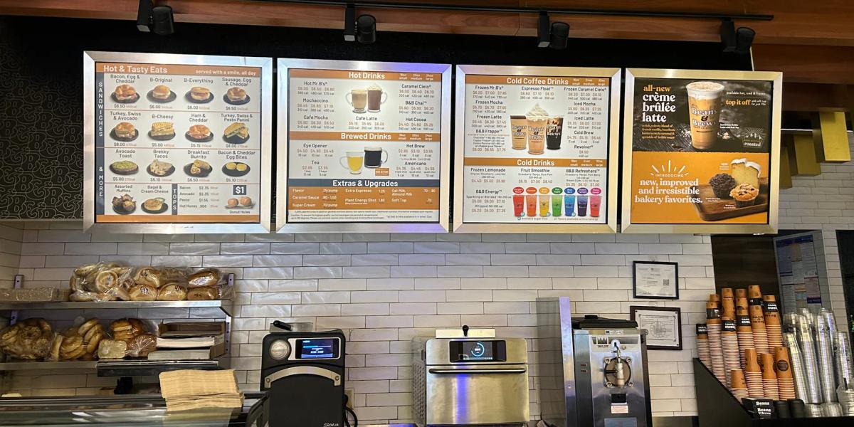 Illuminated café menu boards displaying food and beverage offerings above a service counter.