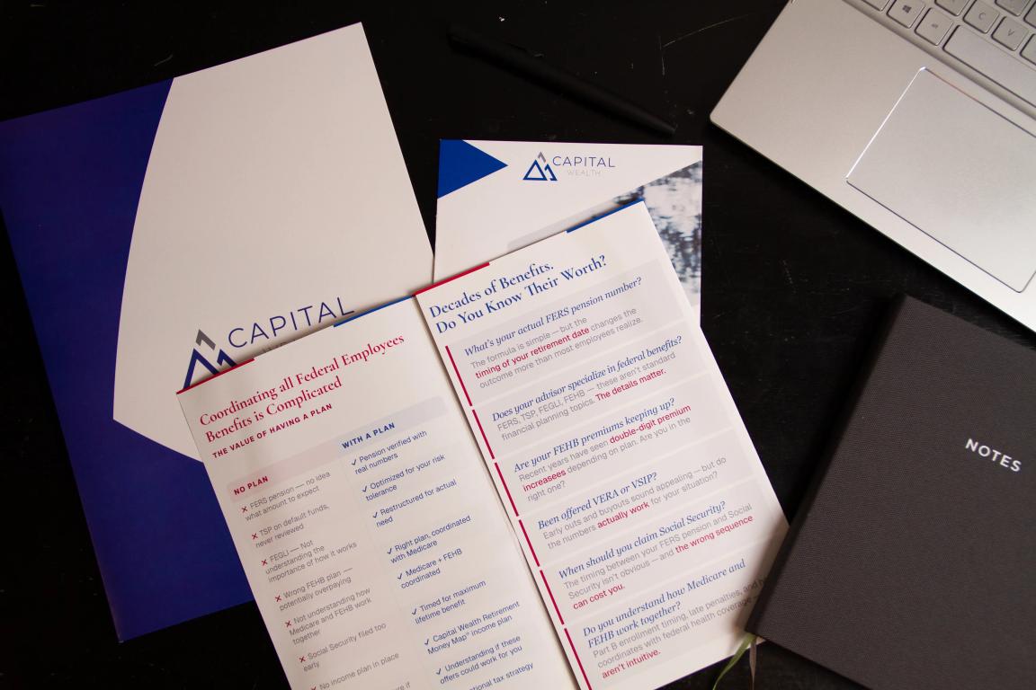 Printed brochures, presentation folders, and business stationery arranged on a desk next to a laptop.