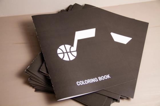 Stack of black coloring books with the Utah Jazz note-and- basketball logo in white and "Coloring Book" across the bottom.