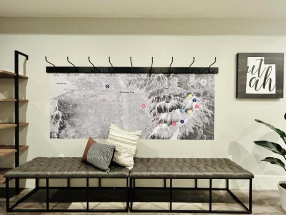 Floor-to-ceiling alpine graphic reading "Send it" with the Basecamp SLC logo, fitted with ski racks holding skis and poles.