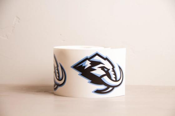 Roll of white vinyl printed with repeating Utah Mammoth logos — a mammoth head in black and light blue with mountain peaks and curved tusks.