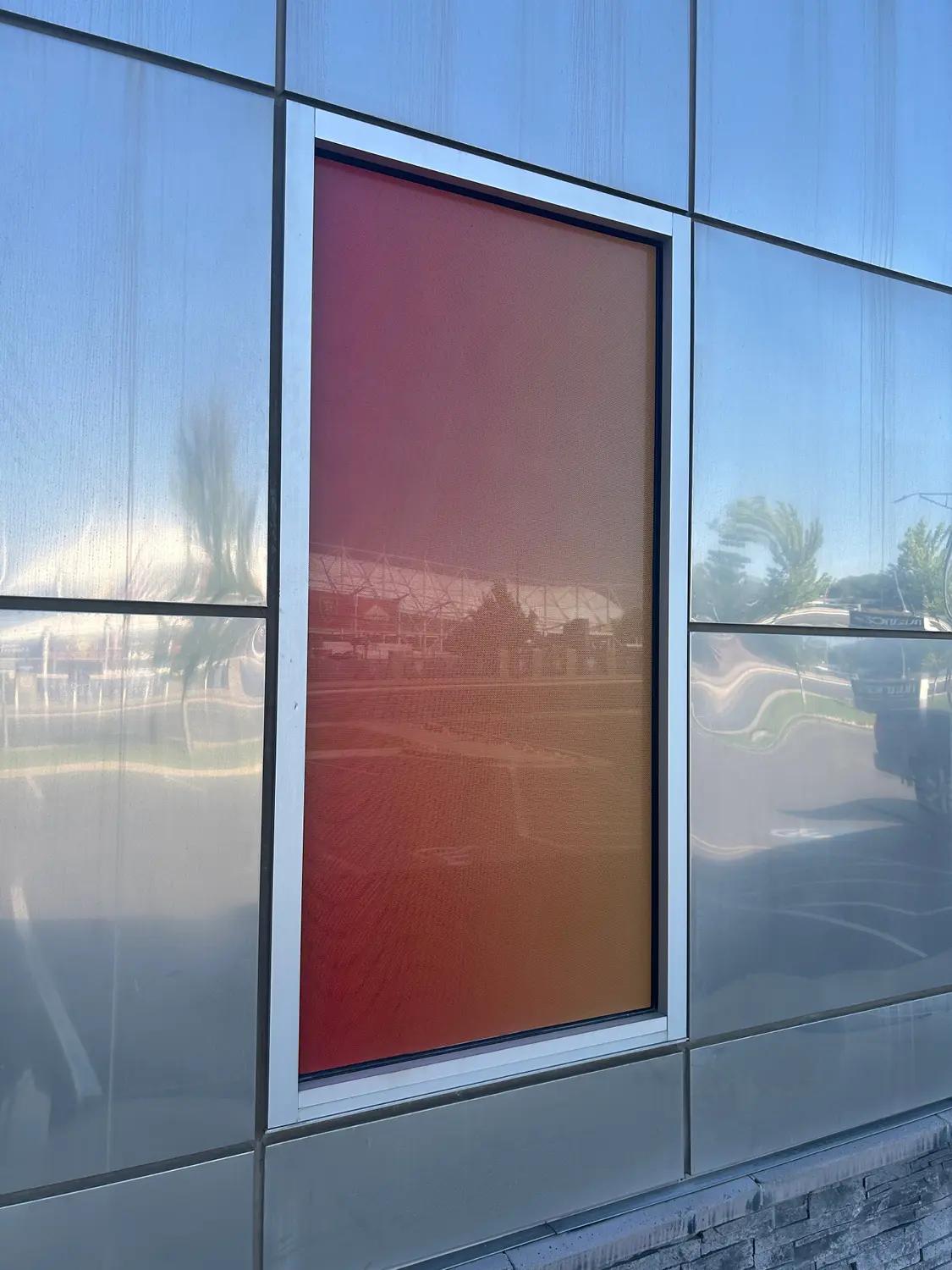 Perforated window vinyl with a vibrant printed color gradient installed on a commercial building window.