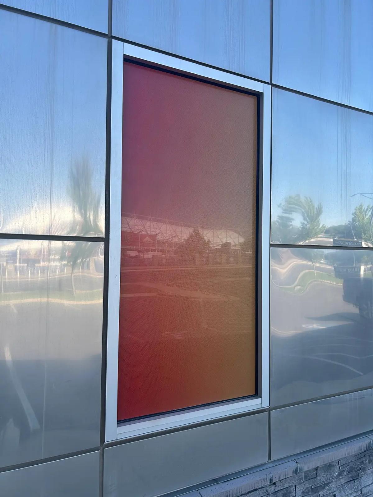 Perforated window film printed with a color gradient installed on a commercial building window for decoration.