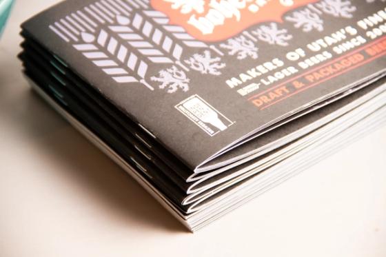 Corner of a stack of Bohemian Brewery booklets showing the Certified Independent Craft seal and the stitched spine edge.