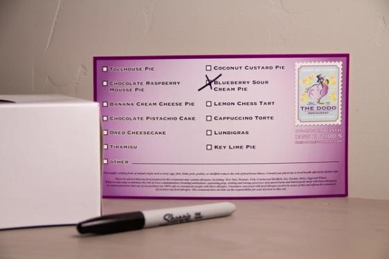 The Dodo dessert label propped beside a white bakery box, with Blueberry Sour Cream Pie marked in black permanent marker.