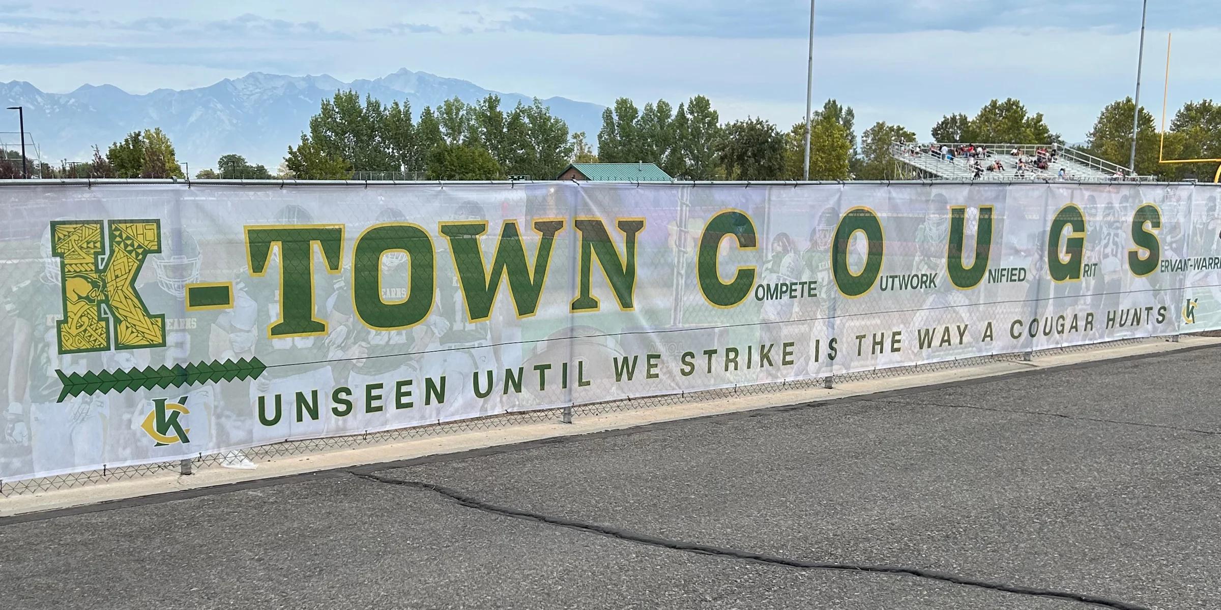 Large-format custom mesh banner printed for fence advertising at schools, sports venues, and outdoor events.