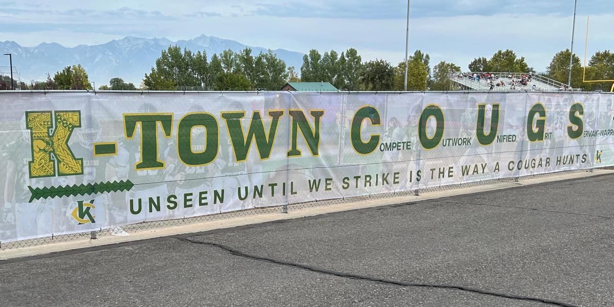 Large-format custom mesh banner printed for fence advertising at schools, sports venues, and outdoor events.