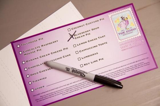 Overhead view of a Dodo dessert label resting on its liner sheet with a marker laid across it.