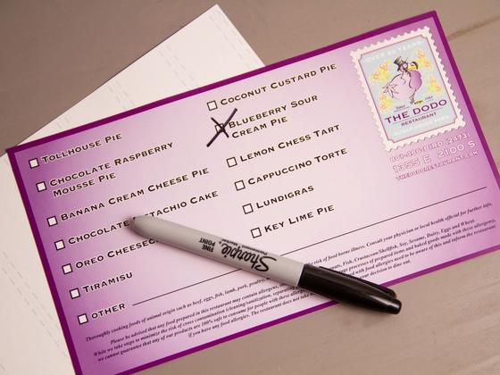 Overhead view of a Dodo dessert label resting on its liner sheet with a marker laid across it.