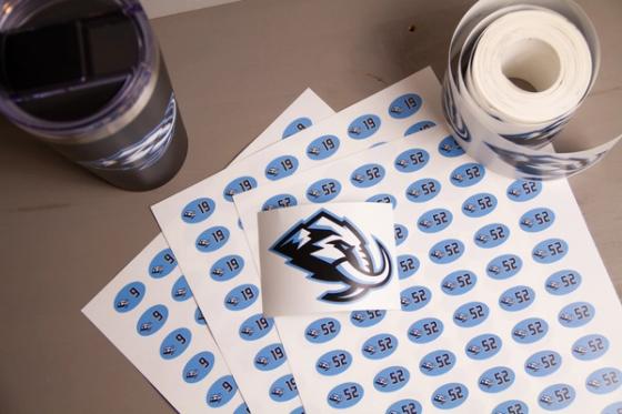Sheets of oval number labels reading 9, 19 and 52, each with a small mammoth logo, fanned beside a logo decal, a roll of vinyl and a branded tumbler.