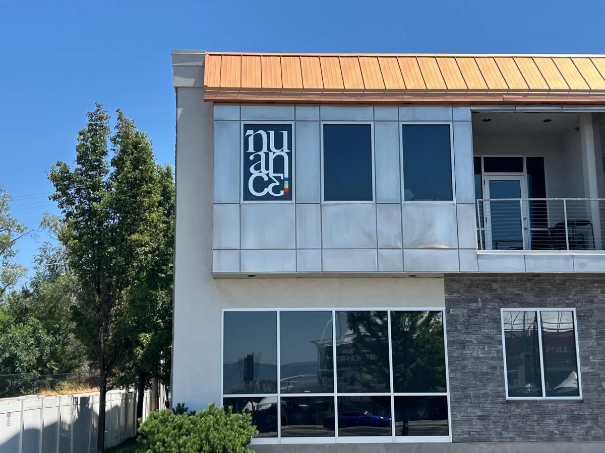 Exterior commercial building with large window graphics displaying a business logo on upper-story windows.