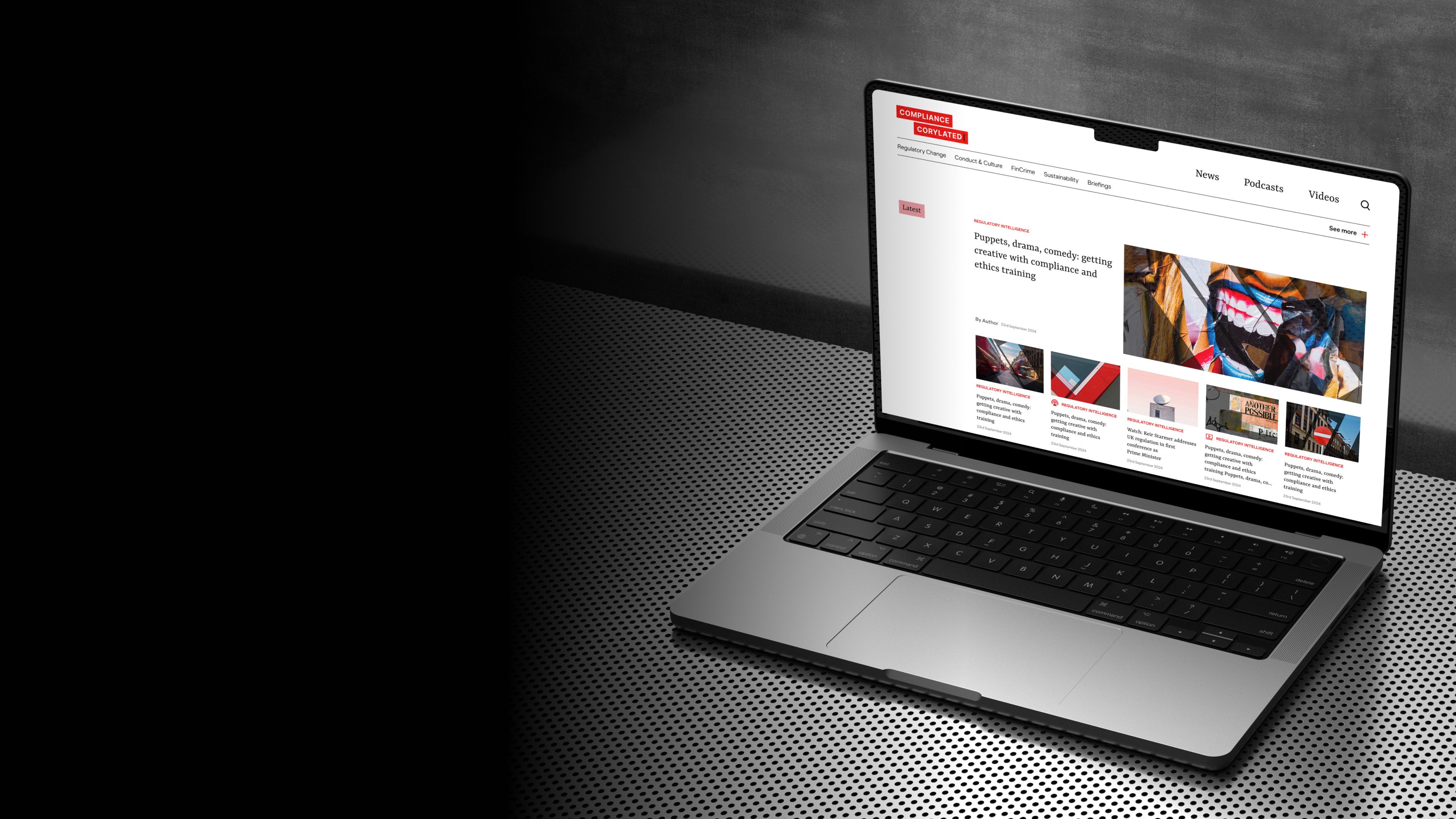 Compliance Corylated news site on a laptop, showing a lead story above a grid of articles