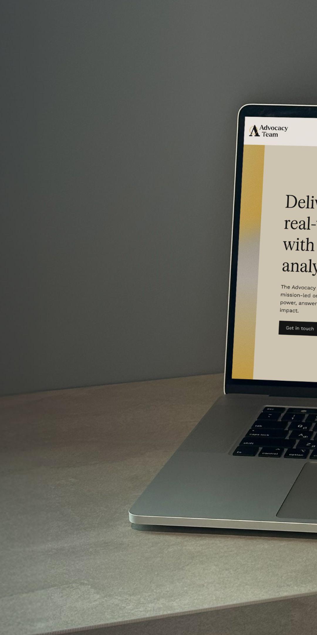 The Advocacy Team homepage on a laptop, headlined "Delivering real-world impact with cutting-edge analysis"
