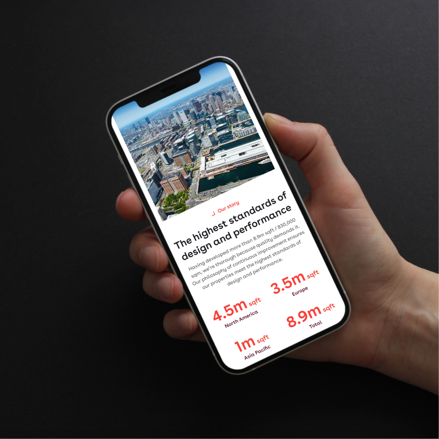 Hand holding a phone showing Pembroke's "Our story" page, with an aerial city photo and floor space figures by region
