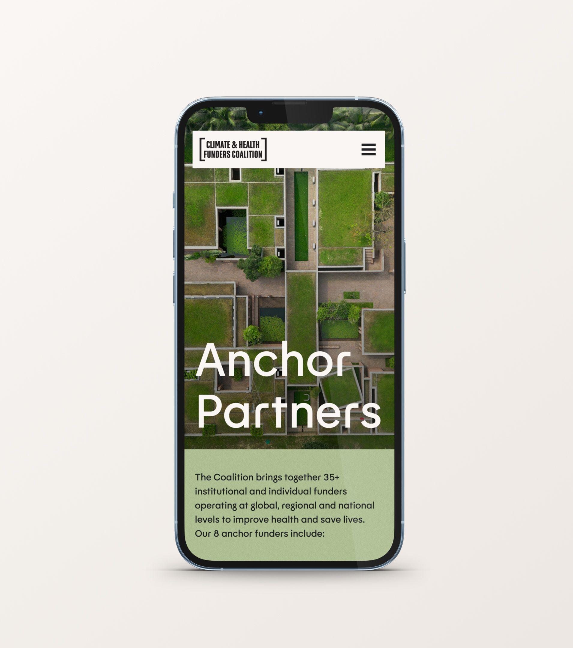 Coalition "Anchor Partners" page on a phone, set over an aerial photo of green rooftops