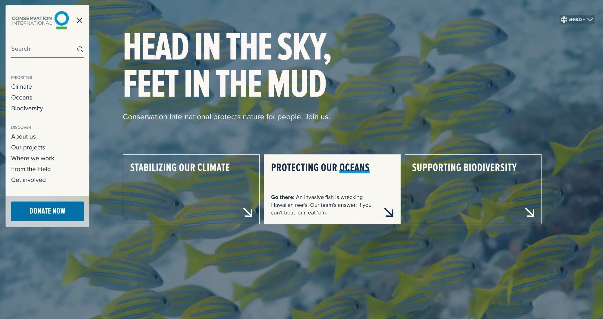 Conservation International's homepage: "Head in the sky, feet in the mud" over a shoal of fish, with the menu open and the three priorities, climate, oceans and biodiversity, as ways in