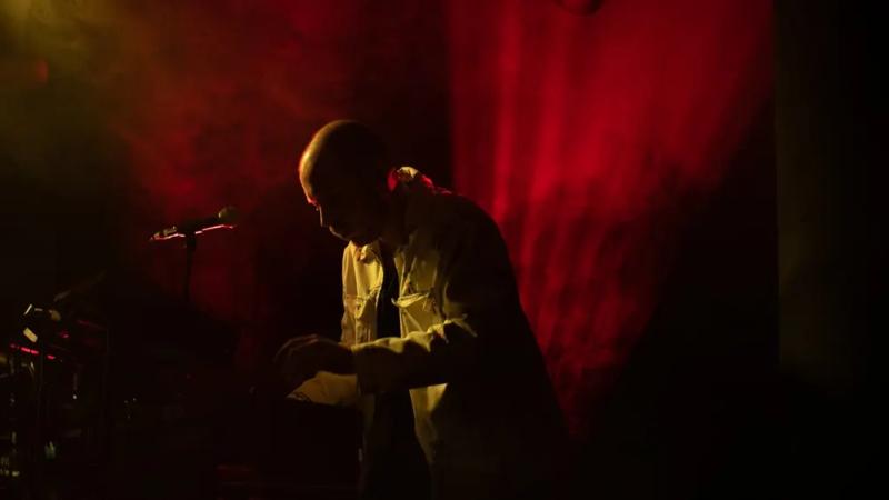 Un musicien de King Child sur scène en lumière rouge.