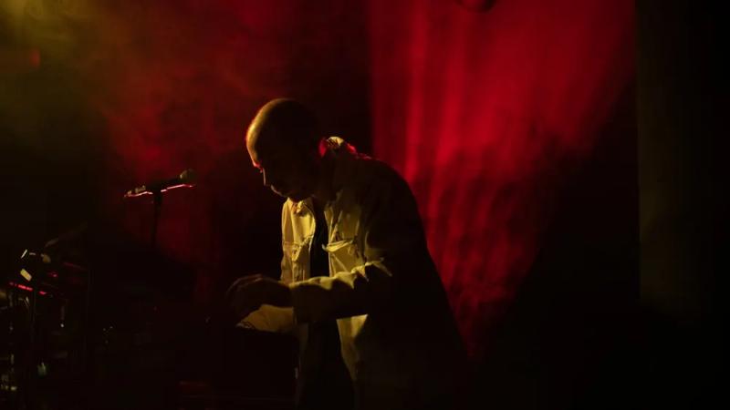 Un musicien de King Child sur scène en lumière rouge.