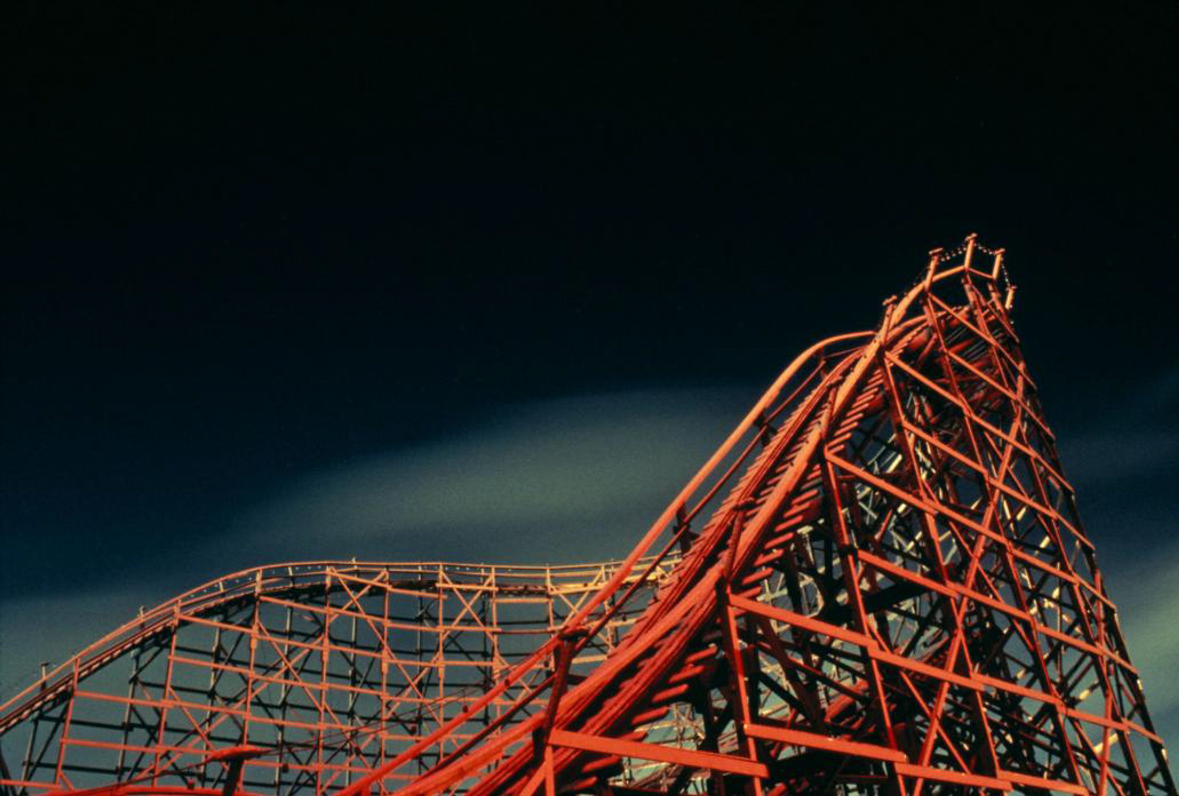 Roller coaster and red neon reflected on snow.