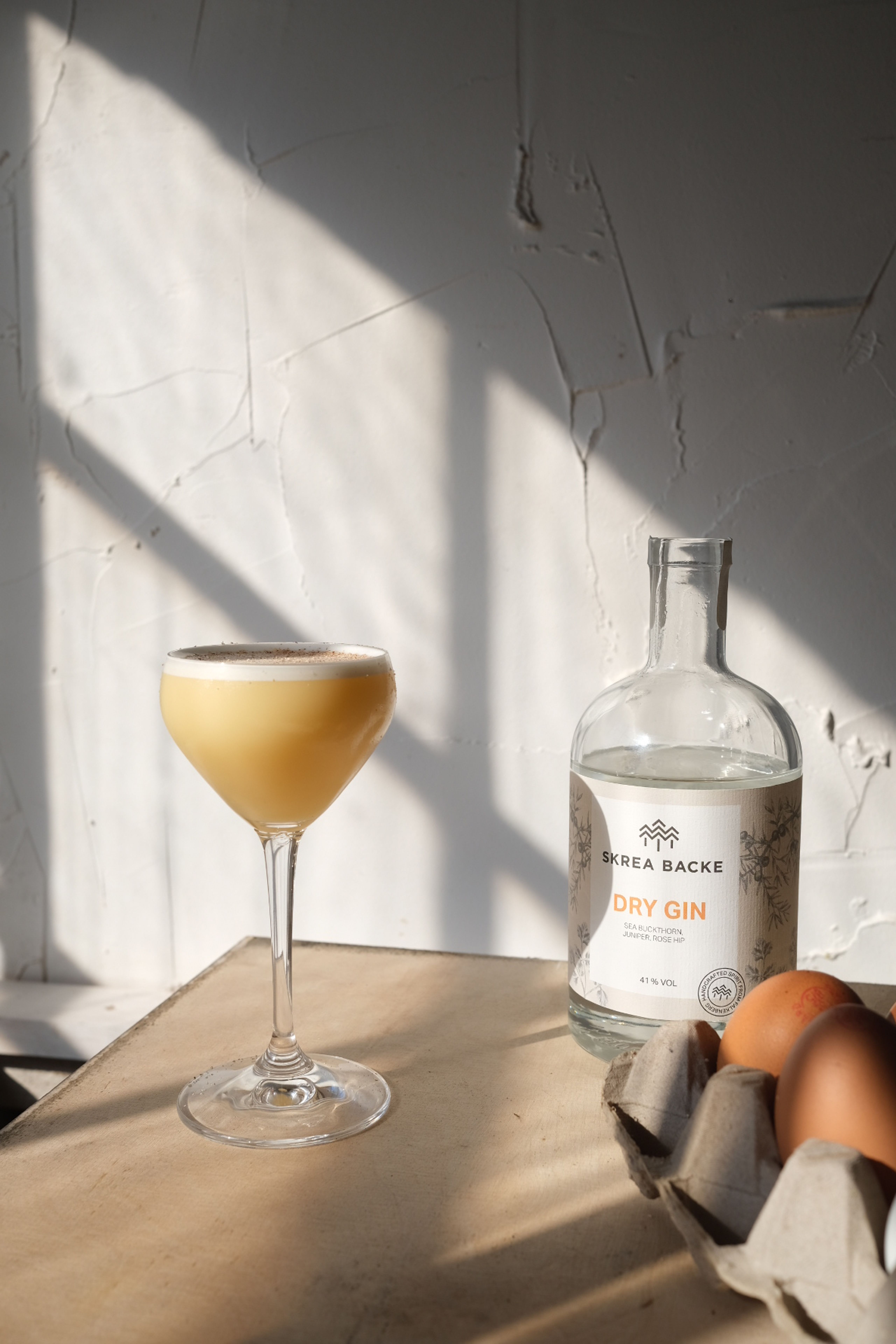 Bild på Skrea gin flip med en flaska dry gin i bakgrunden