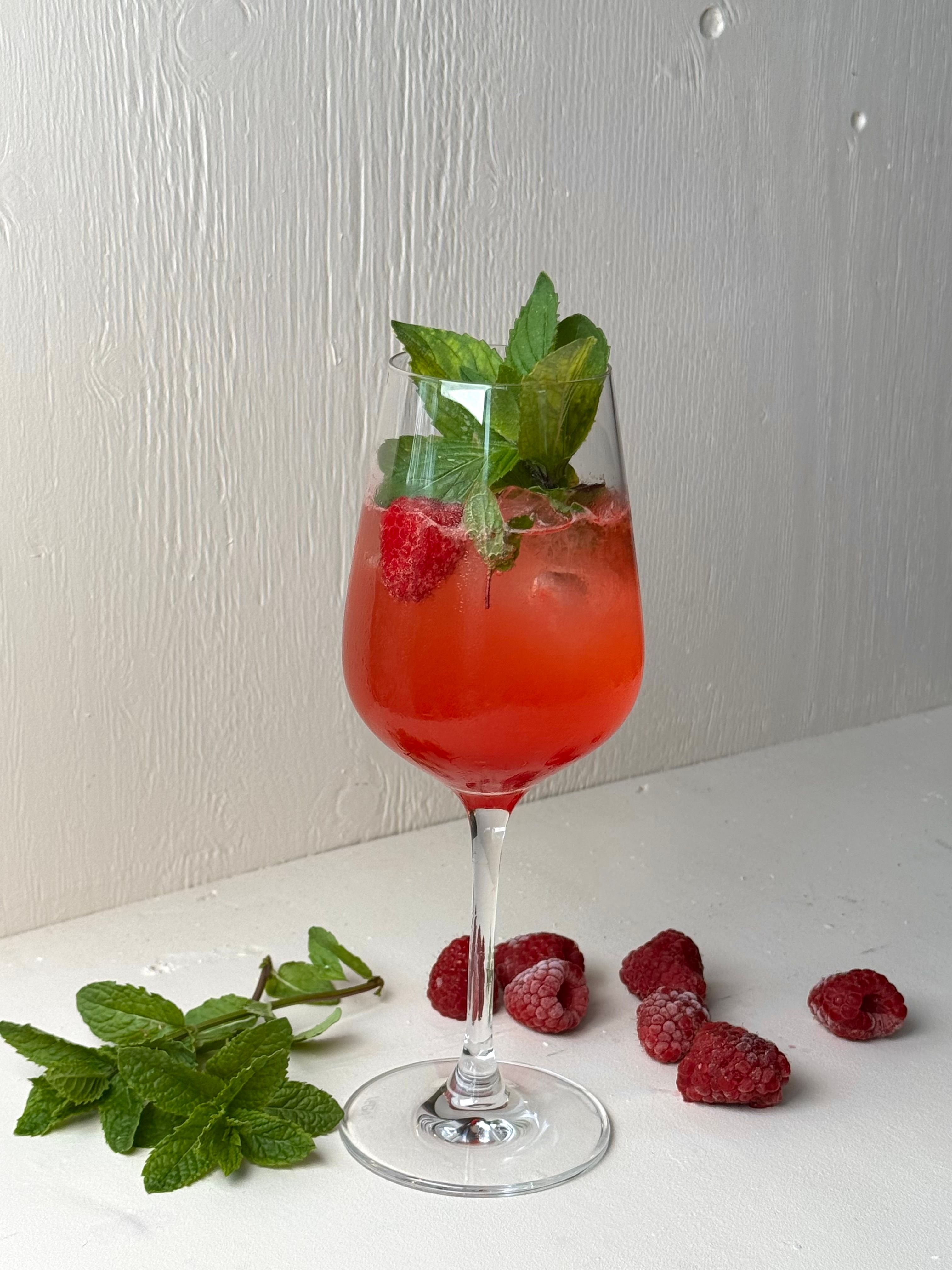 Bild på en somrig drink med fläder, hallon, mynta och gin