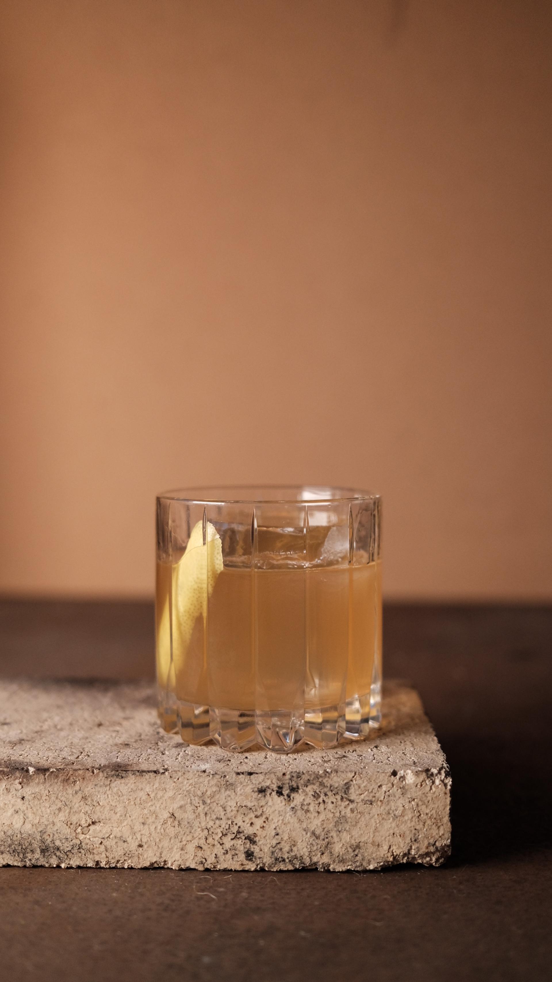 Drinken old honey i ett rocksglas med en skiva citron och en stor isbit.