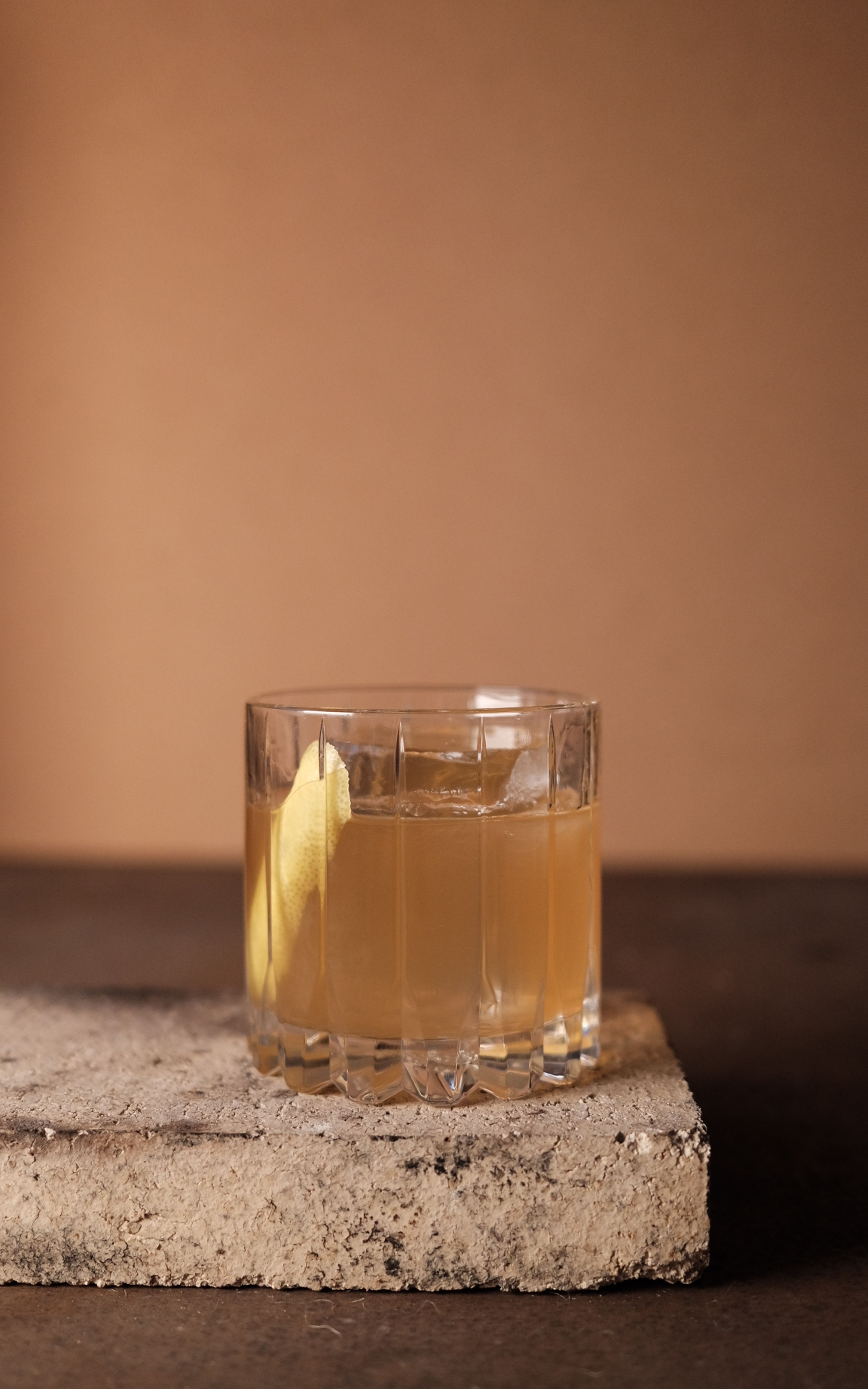 Drinken old honey i ett rocksglas med en skiva citron och en stor isbit.