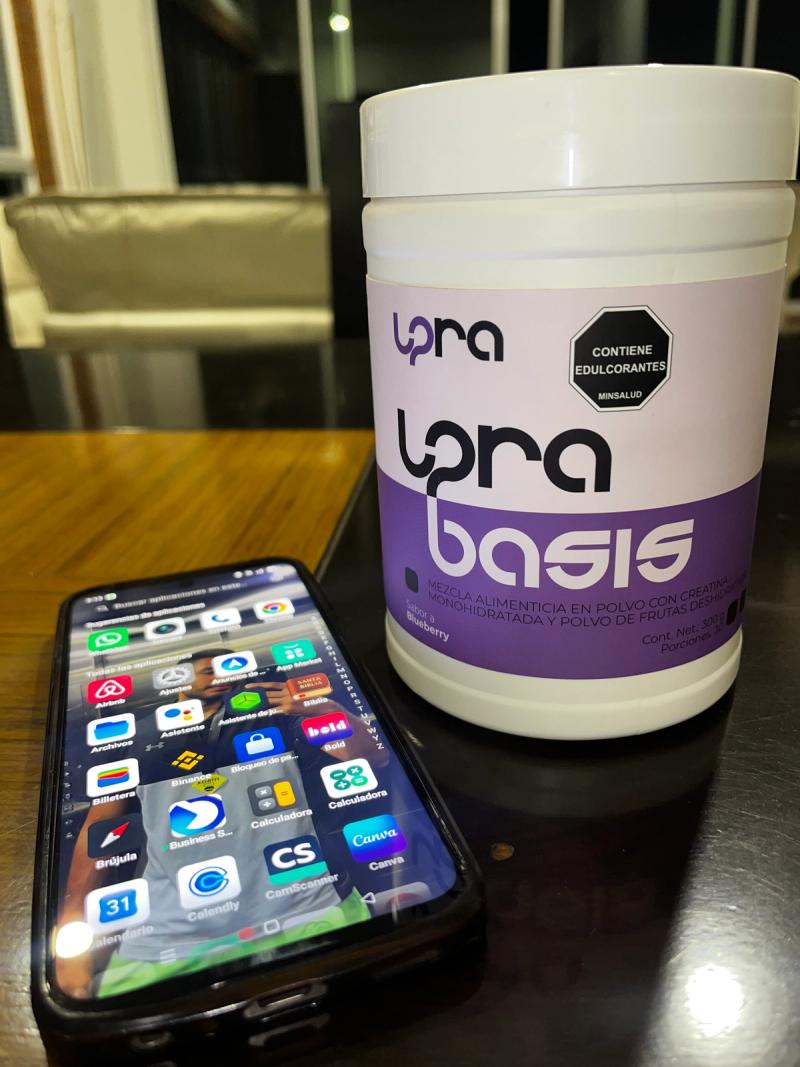 Tarro de UPRA Basis y un celular sobre una mesa.