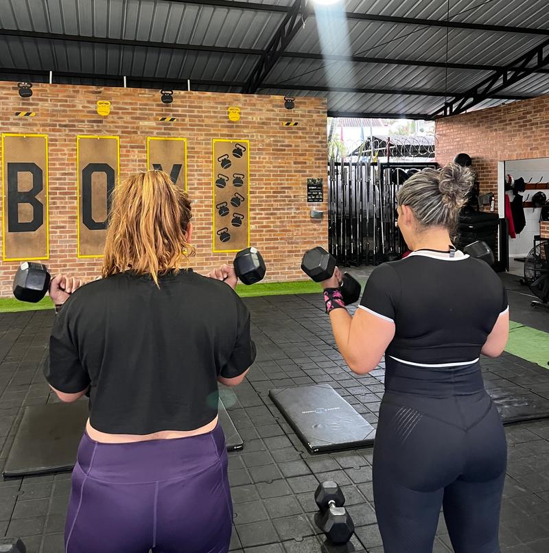 Personas entrenando juntas en un box, de espaldas, con luz de la mañana