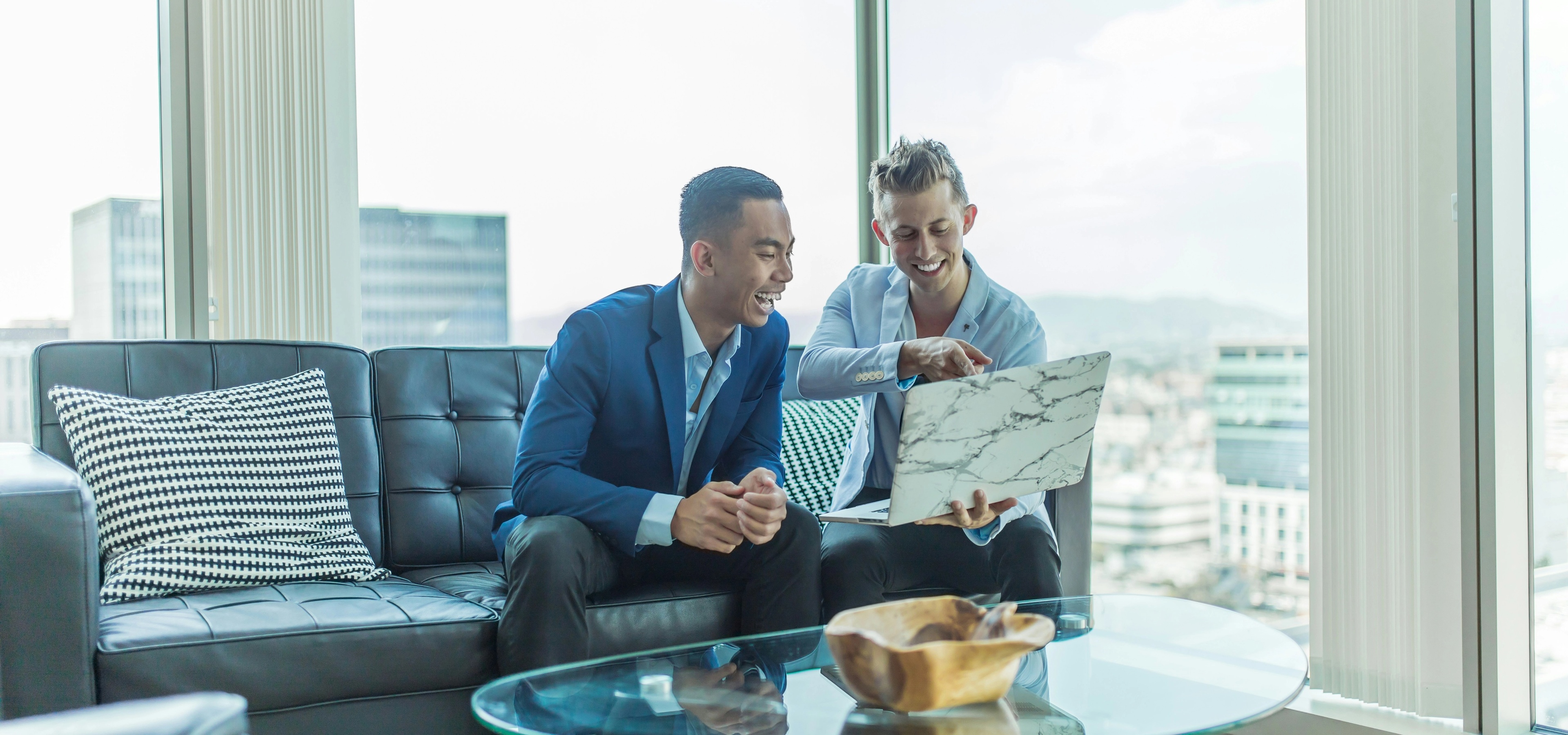 Two private equity professionals are working on their laptops building a buyout strategy.