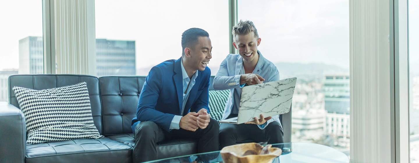 Two private equity professionals are working on their laptops building a buyout strategy.