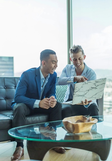 Two private equity professionals are working on their laptops building a buyout strategy.