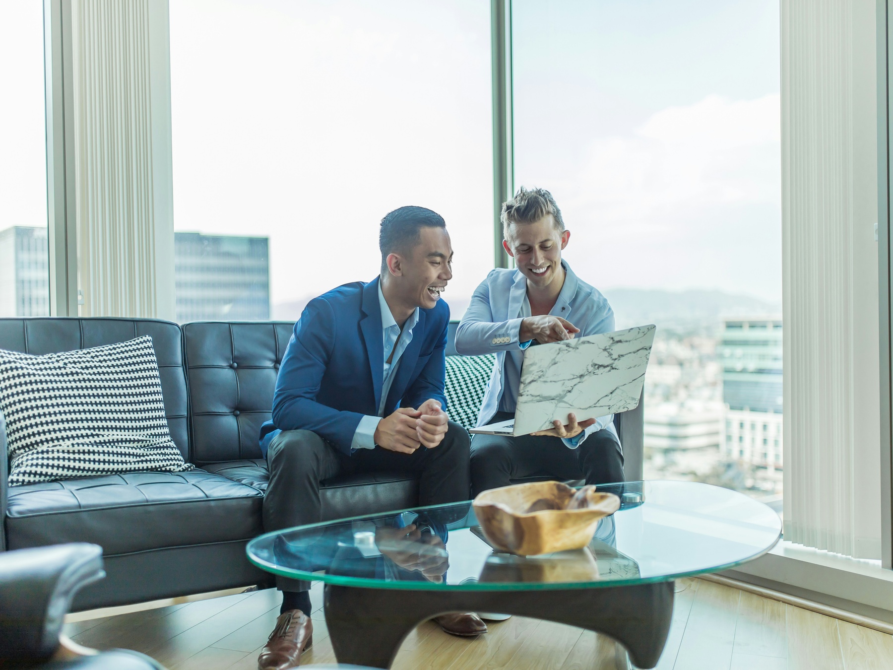 Two private equity professionals are working on their laptops building a buyout strategy.