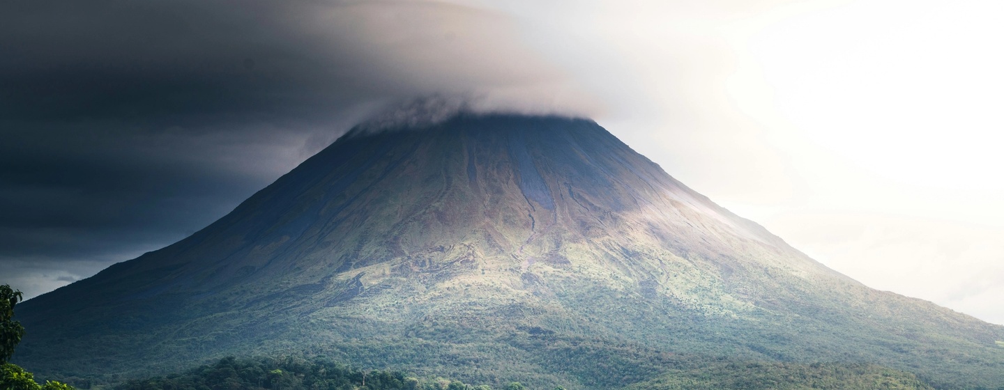 A view of Arenal Volcano, a famous symmetric stratovolcano in Costa Rica, obscured by clouds.