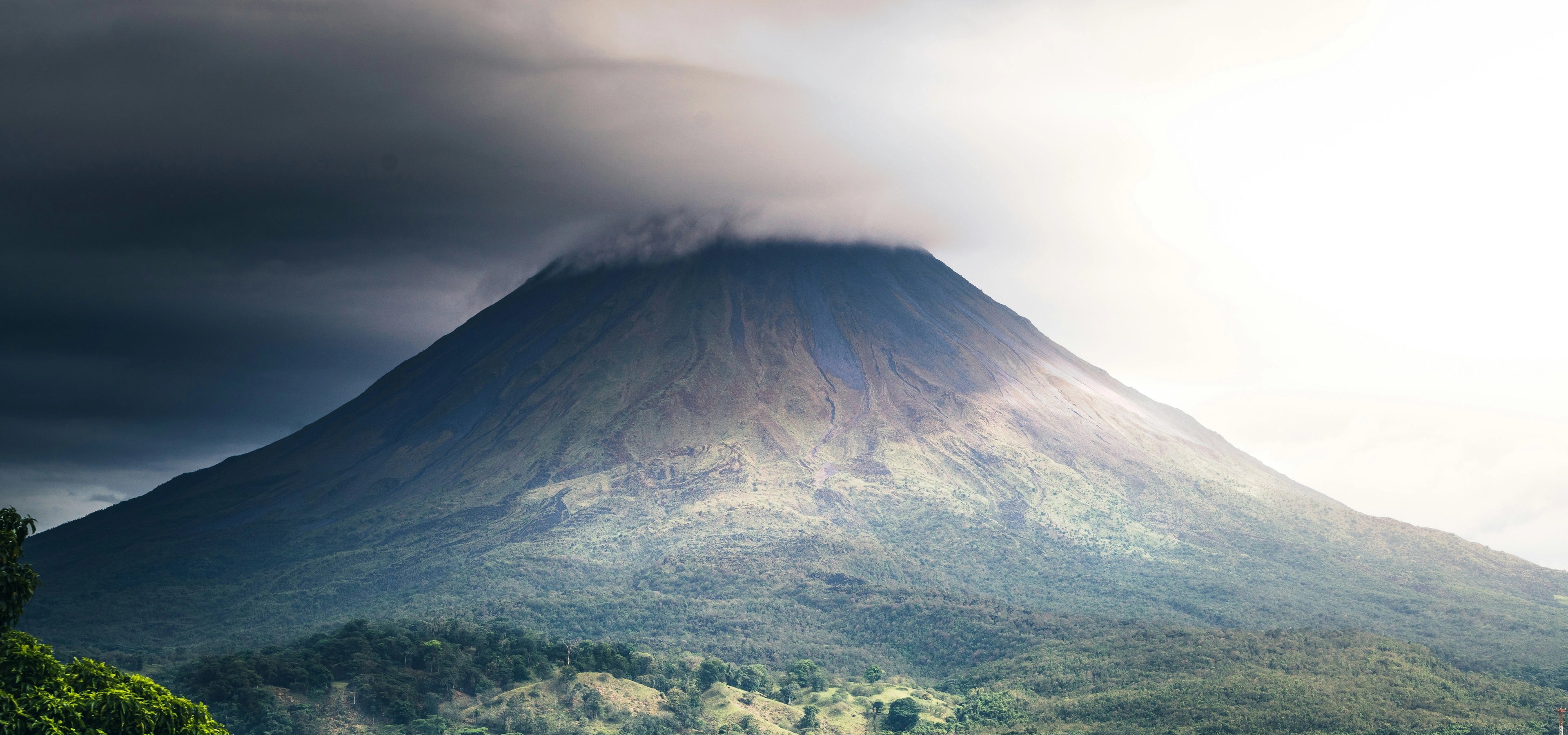 A view of Arenal Volcano, a famous symmetric stratovolcano in Costa Rica, obscured by clouds.