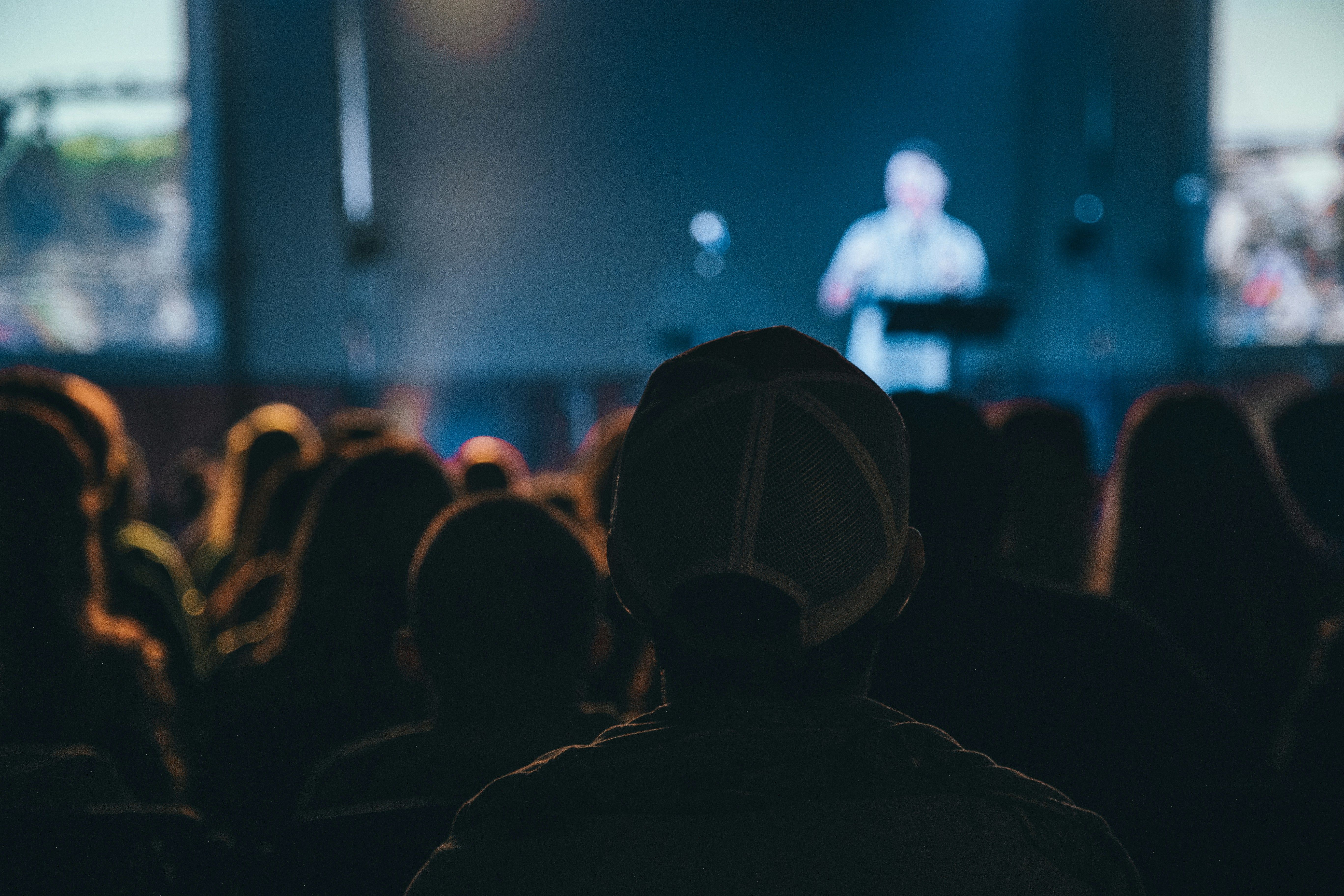 Attendees pay attention to a speaker on the main stage of a conference.