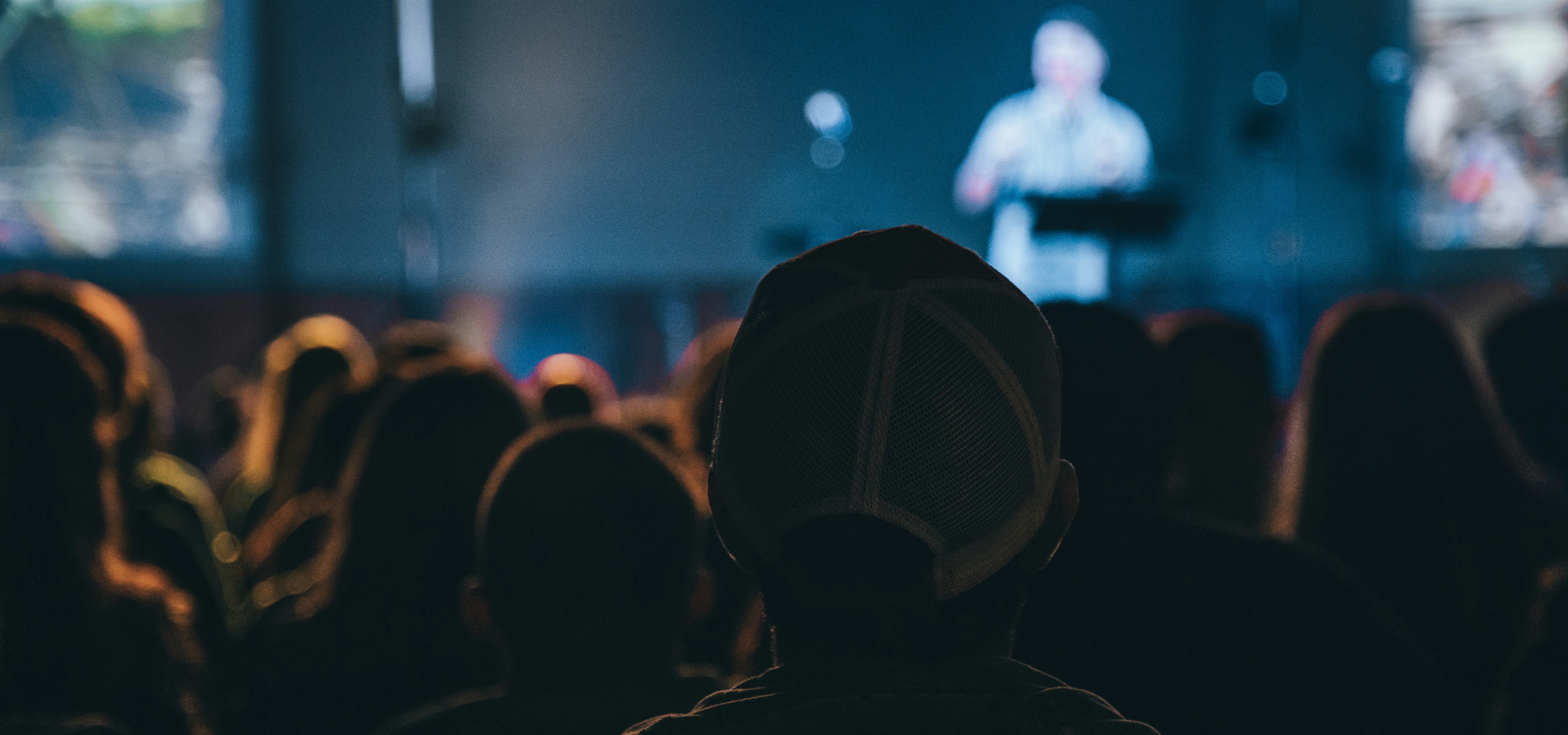 Attendees pay attention to a speaker on the main stage of a conference.