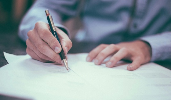 Person seated at table signing contracts