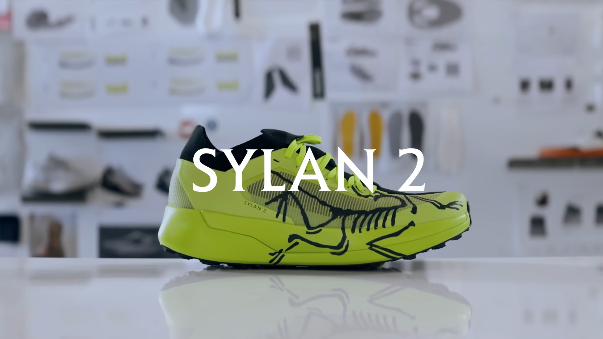 Neon yellow and black running shoe with a skeleton design and "SYLAN 2" text overlay.